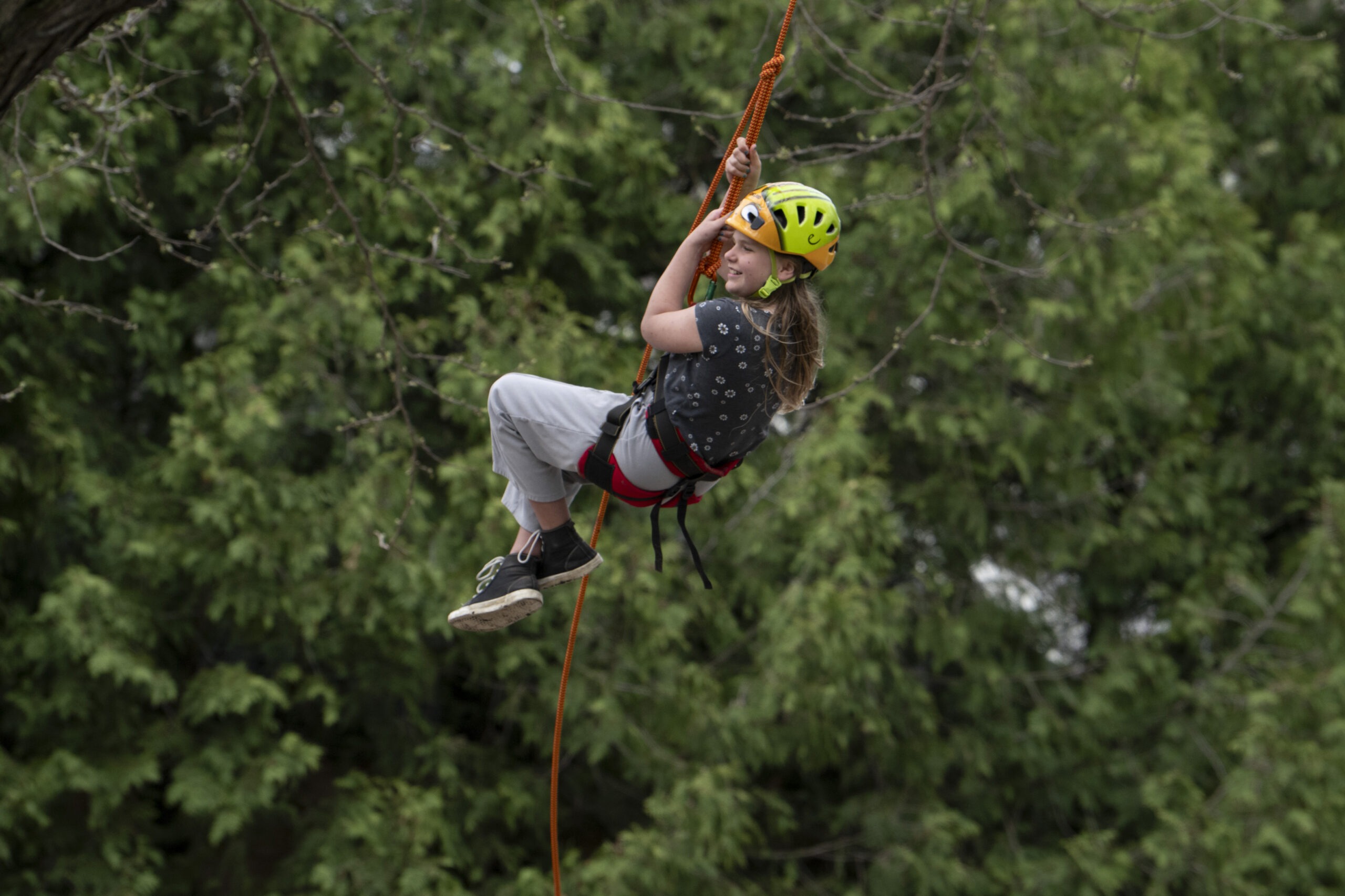 A kid swinging from a harness wearing a helmet